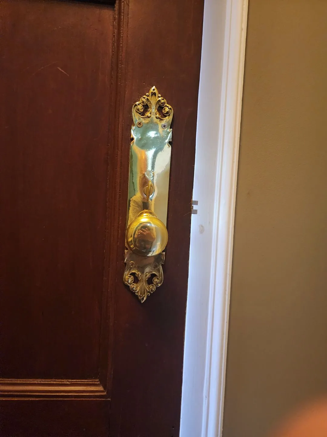 Ornate brass lockset fitted to a dark wood residential door
